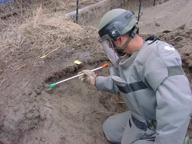 soldier using brush to expose mine.