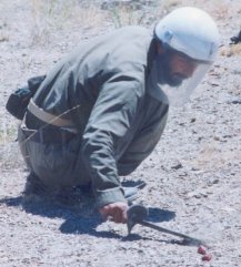 Afghan deminer squatting